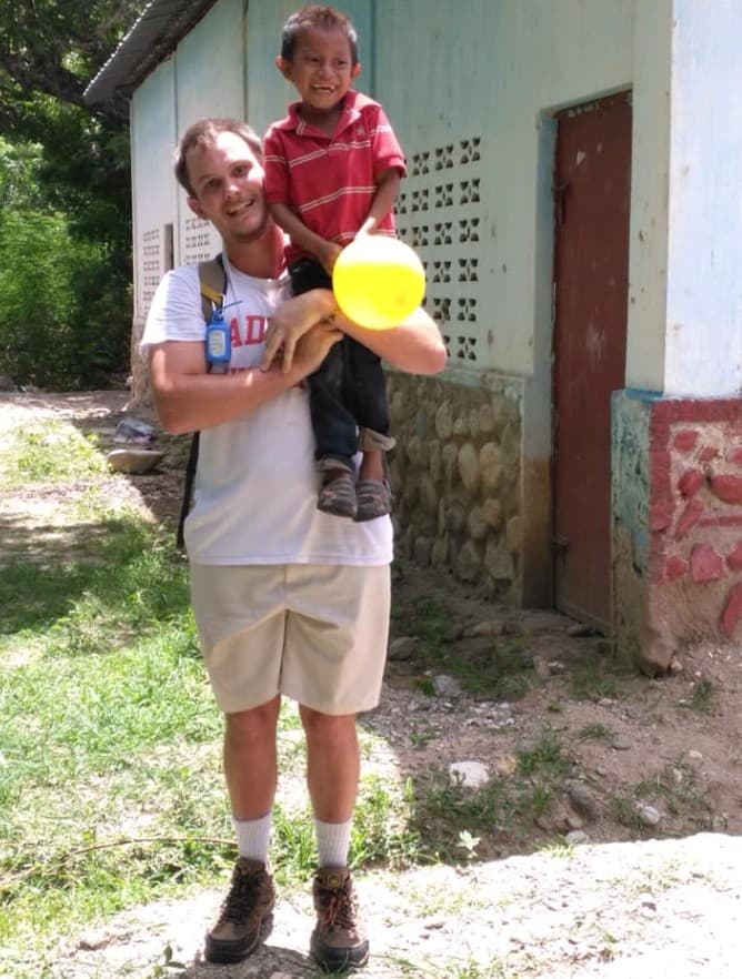 James Kasza lifting a smiling young boy in Guatemala
